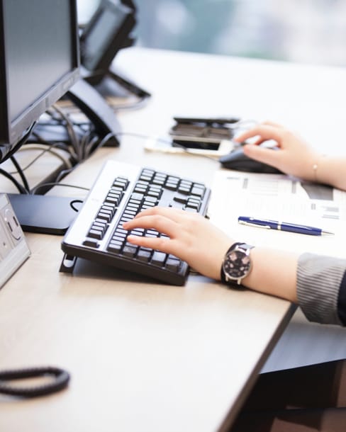 Woman at desk, focusing on hands on keyboard