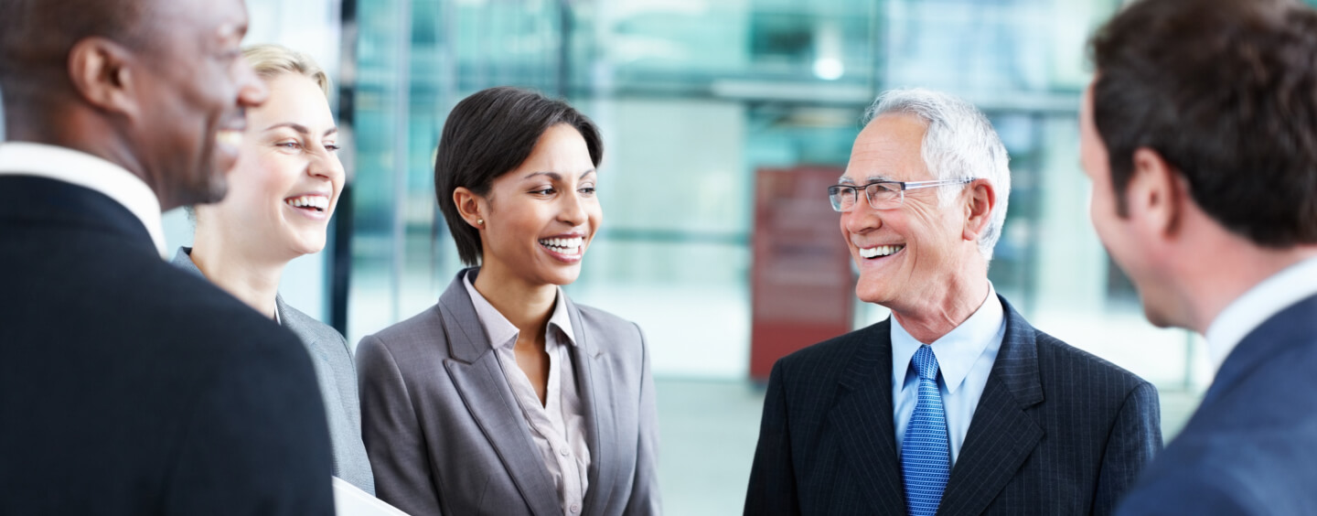 Diverse team of financial advisors engaged in conversation, smiling while working together in a corporate setting.