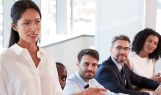 Woman presenting next to co-workers in corporate office