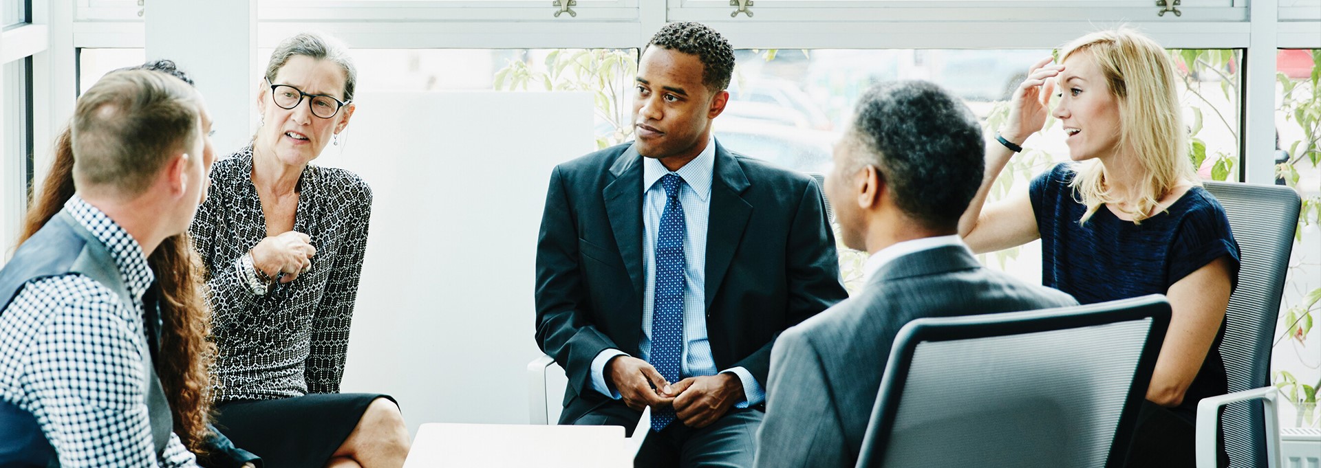 Group of financial advisors sit around a table in animated discussion