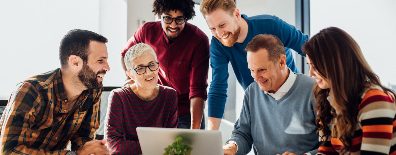 Group of coworkers looking at a laptop smiling