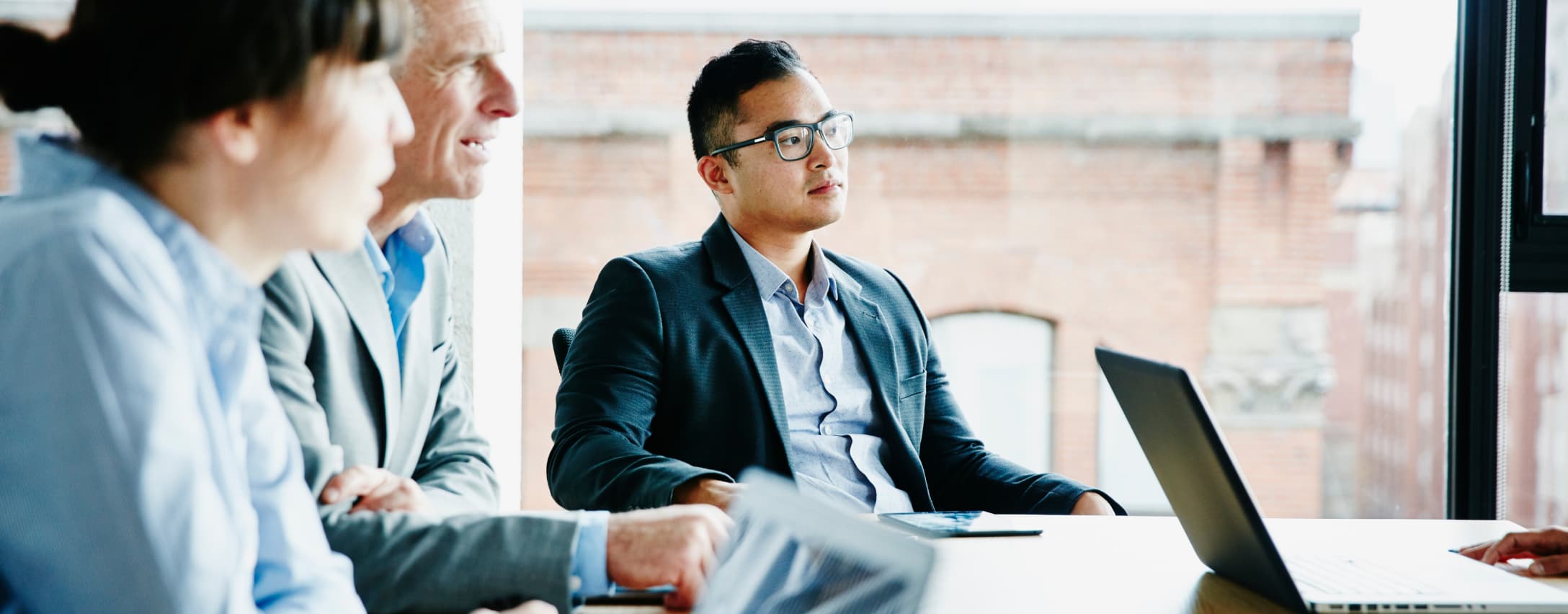 Group of people listening to a person presenting with a laptop