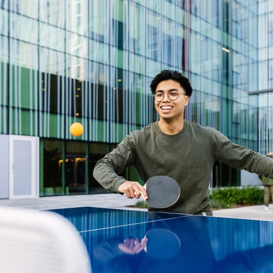 A smiling man competes enthusiastically in a game of table tennis