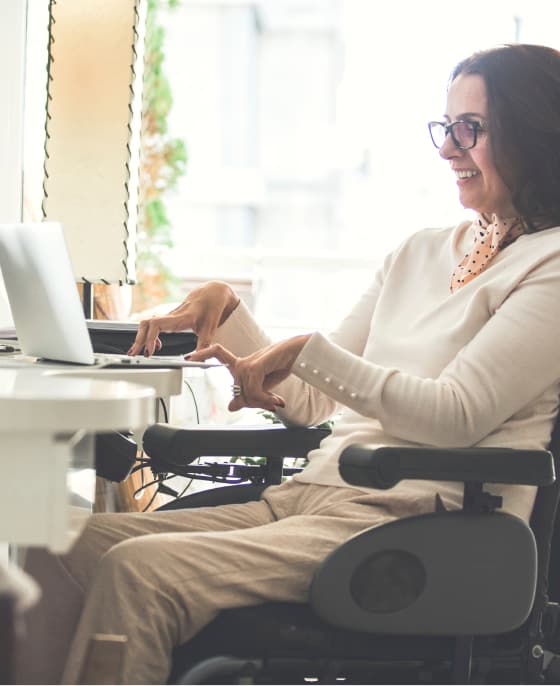 Woman in wheelchair works at her computer desk