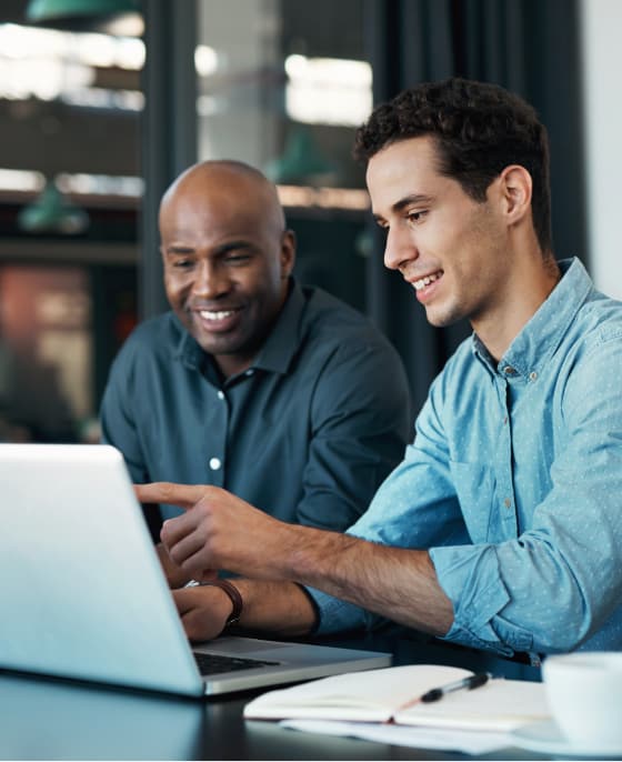 Two men in business attire work at a laptop