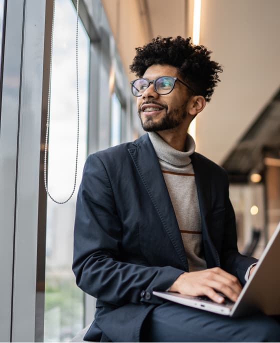 Man on laptop looking out window