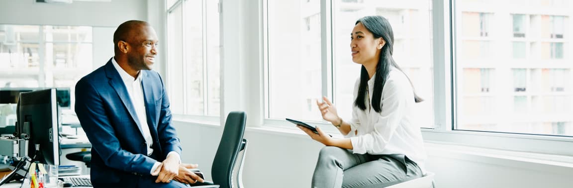 Woman on tablet talking to man in blue suit