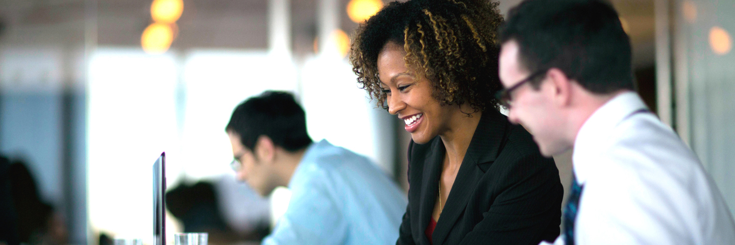 Woman at laptop laughing with coworker