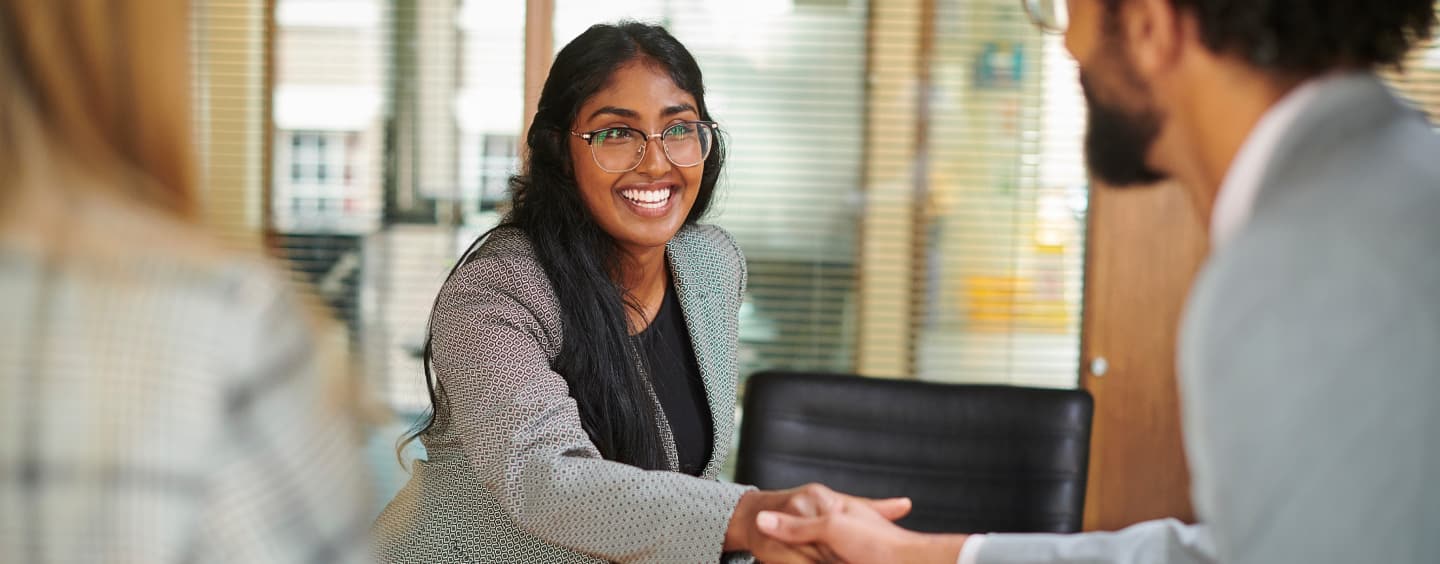 Woman with glasses smiling at coworker