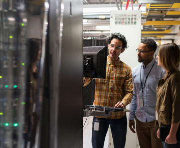 Two team members learning from professional in server room