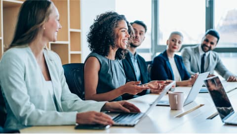 Happy group of financial analysts talking around a conference room table