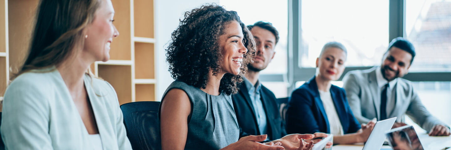 Happy group of financial analysts talking around a conference room table