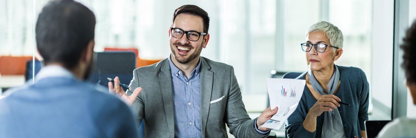 An excited businessman holds up paperwork to show his team