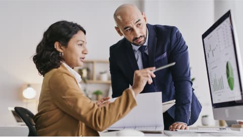 Woman shows a man charts and diagrams on her computer screen