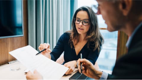 Woman pointing at paperwork and discussing with team