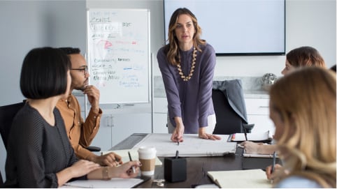 Woman leaning at conference table discussing strategy with the team