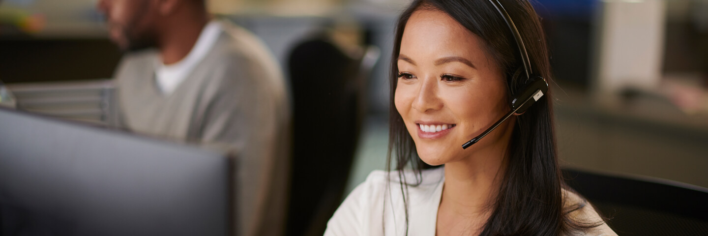 Smiling woman helping a caller while wearing phone headset