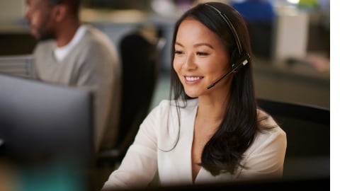 Smiling woman helping a caller while wearing phone headset