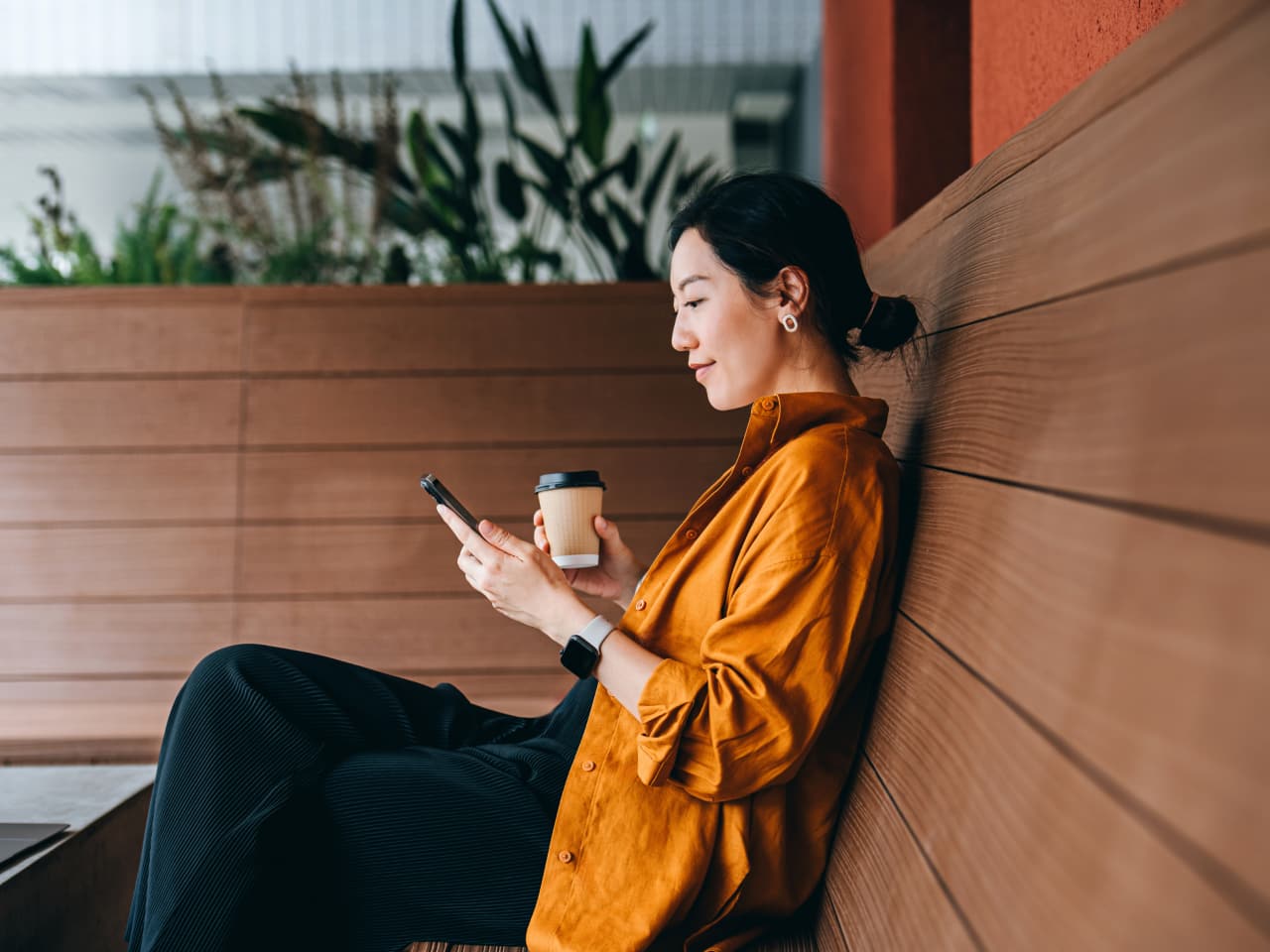 Woman looking at her phone and holding a coffee