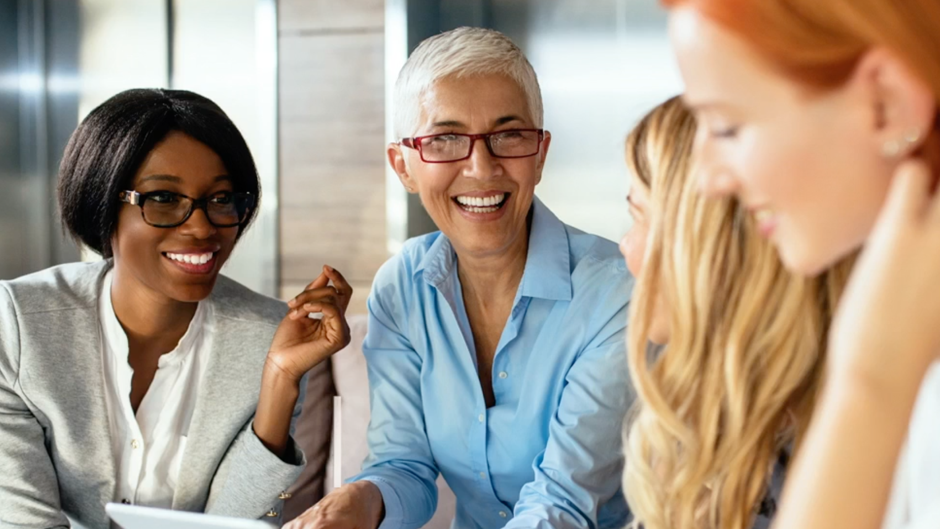 A diverse group of business professional women engaged in a conversation.
